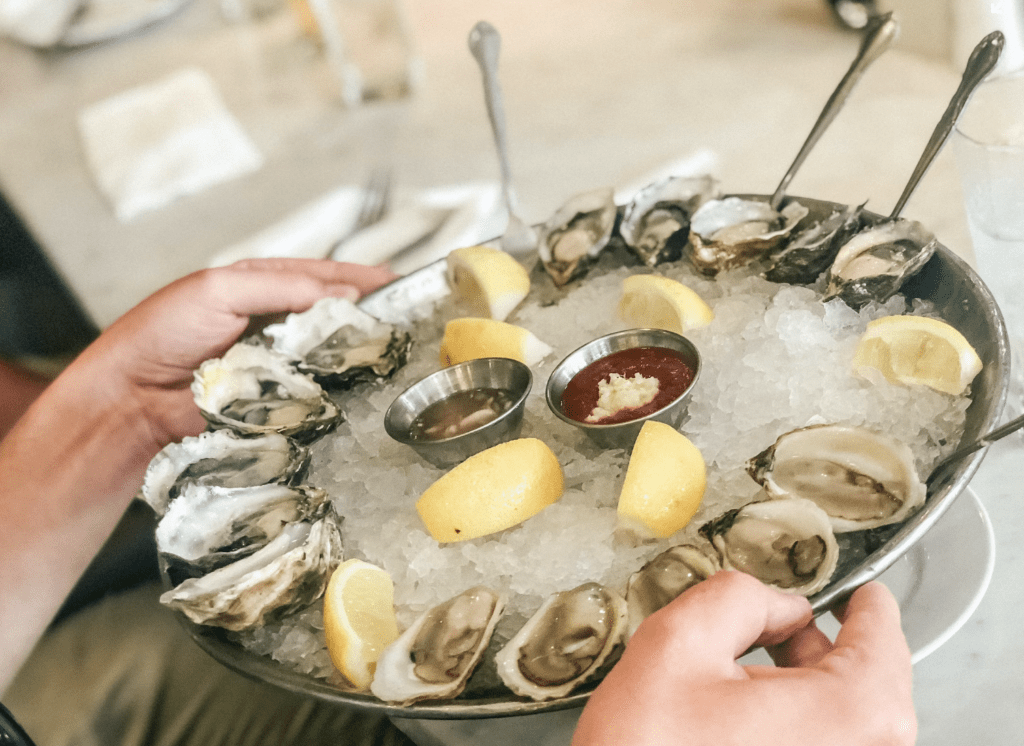 a plate of shucked vancouver island fresh oysters with red sauce and lemons in the middle